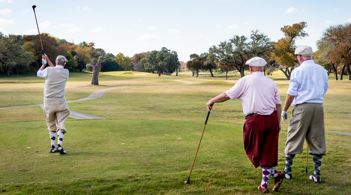 Three individuals enjoying a round of golf on a lush green golf course in Salado, Texas, under the clear blue sky.